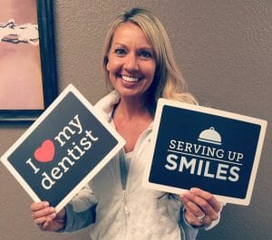 Happy dental patient holding up a sign at Anchorage Dental Group